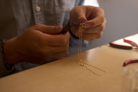 Atelier créateur bijoux fantaisie Shango travaillant un collier plaqué or avec pierre semi-précieuse